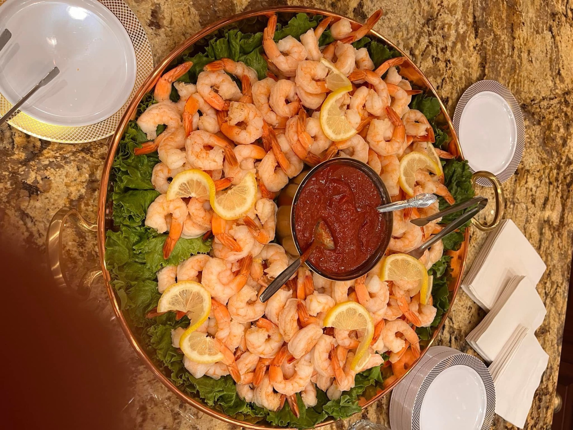 Copper tray of chilled boiled shrimp with cocktail sauce