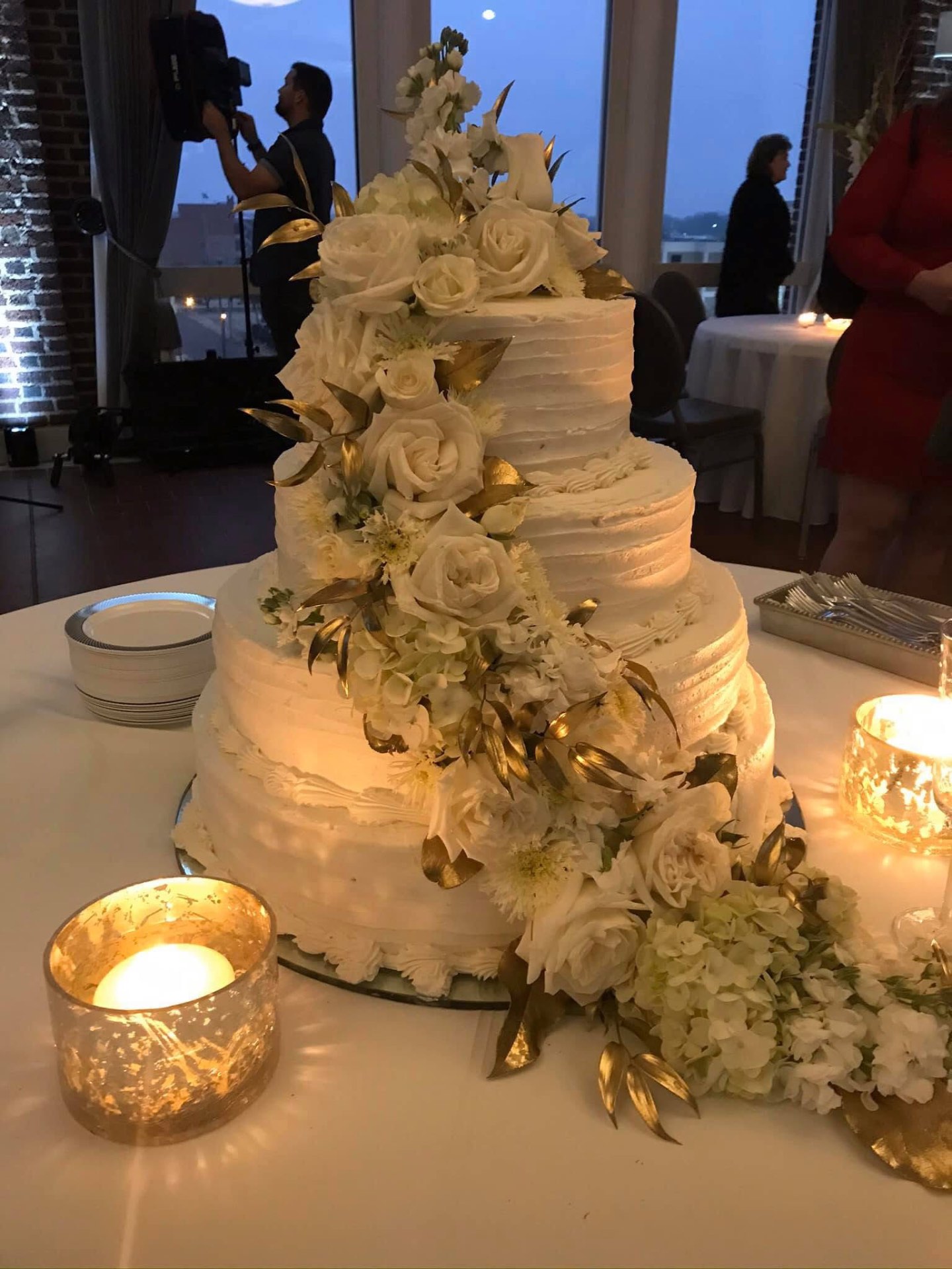 Four-tier white buttercream wedding cake with gold leaves